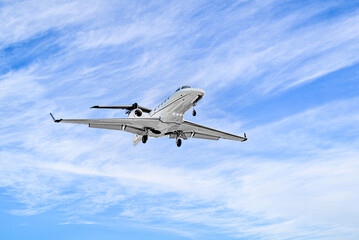 Private business plane flying under blue sky with white clouds