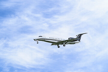 Private business plane flying under blue sky with white clouds