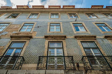 Weathered tiled façade of an old building in Lisbon, Portugal, showing ornamental ceramic patterns and signs of age and decay