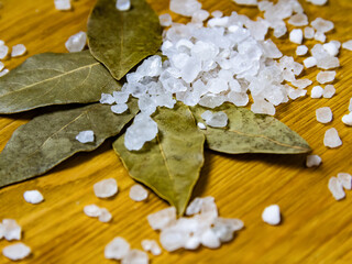 Dried bay leaves and sea salt on a wooden surface 