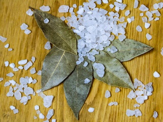 Dried bay leaves and sea salt on a wooden surface 