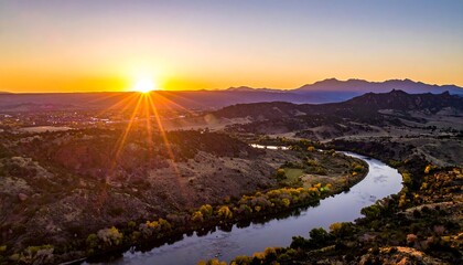 An aerial perspective captures a river snaking through a valley, lit by a vibrant sunset, creating a serene landscape