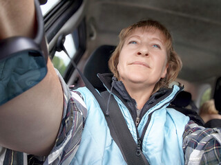 Middle-aged woman blogs about her travel adventures while driving through scenic landscapes