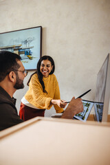 Two architects discussing a project on a computer in an office environment.
