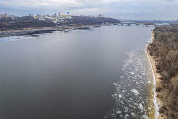 Obraz premium Aerial view of the frozen Dnieper River and Kyiv Pechersk Lavra in winter.
