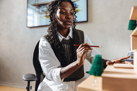 Young architect working attentively on a scale model at her desk