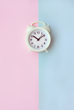 Alarm clock on pink and blue backgrounds. Human circadian rhythms concept. Vertical banner. Selective focus and copy space