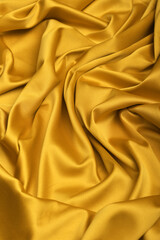 Fototapeta premium Close-up of luxurious yellow acetate satin fabric, heavily draped and folded to showcase its silky texture, rich luster, and flowing nature, ideal for fashion and elegant apparel design.