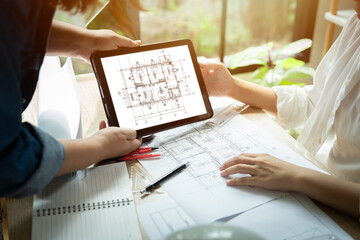 Two people are looking at a tablet with a drawing of a house. One person is holding the tablet and the other person is looking at it. The tablet is showing a drawing of a house with a lot of details
