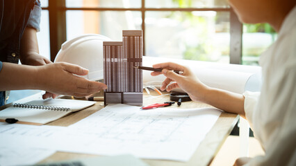 A group of people are working on a building design. They are using pencils and paper to sketch out their ideas. Scene is collaborative and focused