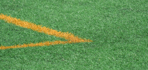 Green synthetic grass, artificial turf sports field with yellow lines.