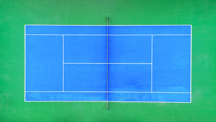 Blue hard court surface for tennis sport, an empty outdoor competition field with white lines, and a net for playing matches, viewed from an aerial top down perspective © Newleks