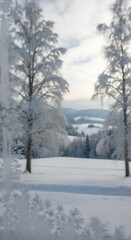 Obraz premium A frosted winter scene features snow-covered trees and a distant mountainous landscape, bathed in soft sunlight. It suggests tranquility