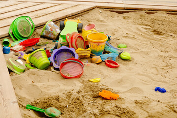 Elhagyott sokszínú gyerek játékok a homokozóban.