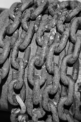 Close-up of heavy rusted metal chains in sunlight. Corroded industrial steel links with rough texture.