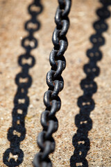 Close-up of dark metal chain casting shadow on concrete. Industrial chain with strong sunlight and sharp shadow.