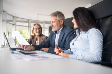 Multiethnic team discussing business strategy around laptop creative office environment collaboration	