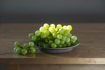 Fresh green grapes on a plate illuminated by backlight, highlighting texture and freshness