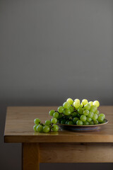 Fresh green grapes on a plate illuminated by backlight, highlighting texture and freshness
