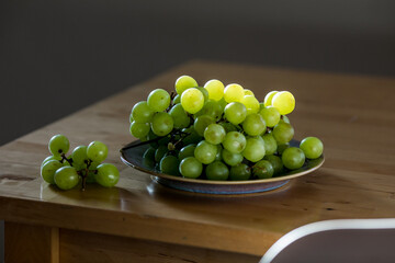 Fresh green grapes on a plate illuminated by backlight, highlighting texture and freshness