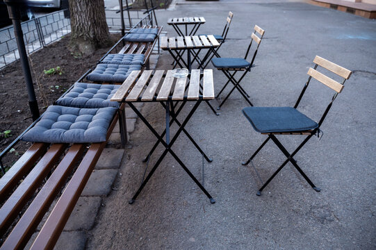 Outdoor seating area with tables and chairs in a row. - Powered by Adobe