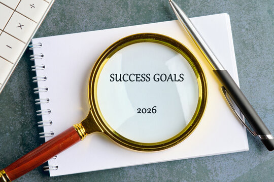 A magnifying glass focuses on the words success goals 2026 written in bold. Nearby, a notebook and pen suggest a plan for aiming high in personal and professional life