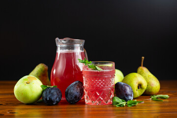 Refreshing fruit drink with plums and pears on a black background © Peredniankina