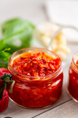 Delicious chili paste with garlic and basil on wooden surface