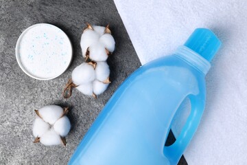 Laundry detergents, towel and cotton flowers on grey table, flat lay