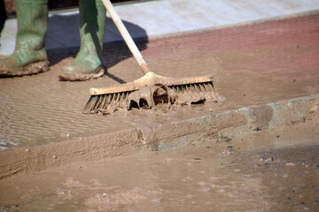 A worker brushes mud off a sidewalk during floods.