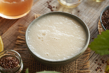 A bowl of homemade natural shampoo with ingredients - flax seed gel, argan oil, apple cider vinegar, nettle and coco glucoside