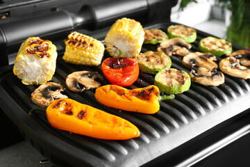 Electric grill with delicious vegetables on table, closeup