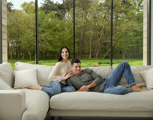 Happy couple resting on sofa near big window at home