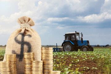 Earning money from agricultural production. Bag with dollar sign and coins against tractor in field