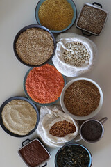 Bowls and bags full of various healthy grains and legumes. Top view.