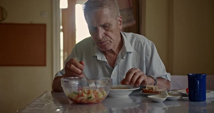 An older man enjoys a healthy and nutritious meal at his home, reflecting a quiet moment of daily routine and independent living.