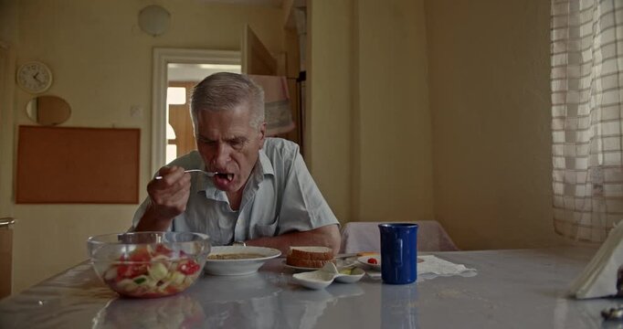 An elderly man thoughtfully eats a nutritious meal in his home, symbolizing routine, independence, and the quiet dignity of a senior's daily life. The scene evokes a sense of peace and reflection.