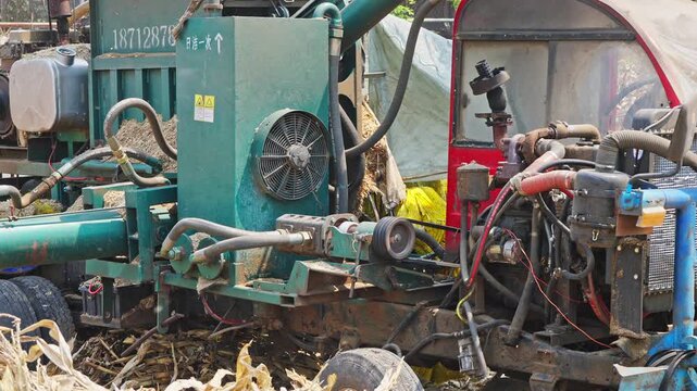 Workers using a machine to crush straw