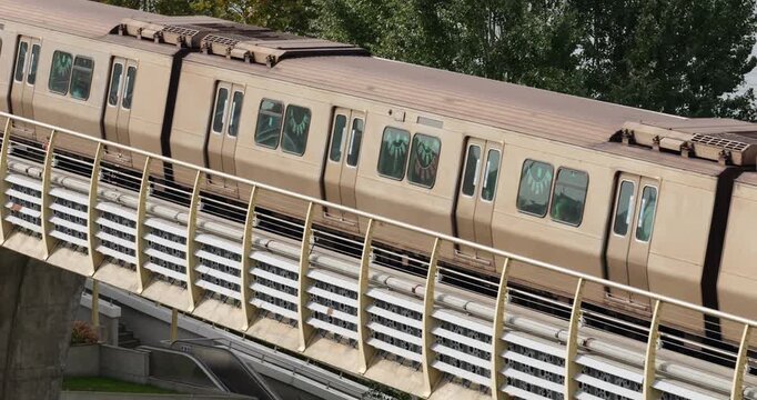 Slow motion medium telephoto tracking shot of subway train traveling along viaduct of Golden Horn Metro Bridge in Istanbul. Camera pans to follow movement of train cars