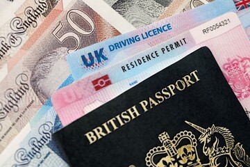 United Kingdom driving license with passport and residence permit card on UK money close up