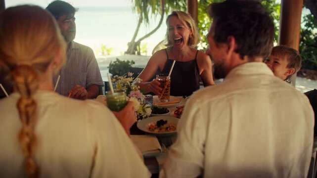 Happy family enjoying tropical breakfast with refreshing fruit juice at a beautiful resort villa