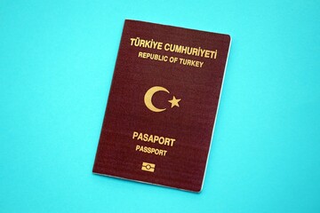 Turkish passport book on light blue paper background close up. Travel document on blue surface