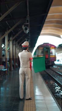 railroad station dispatcher giving green signal for train departure, rail train station attendant waving flag to start journey at busy platform, 4k vertical video