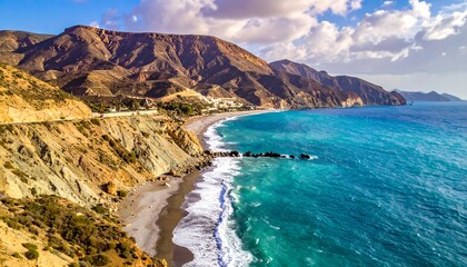Aerial view of a coastal landscape with a sandy beach nestled between rugged, colorful mountains and turquoise ocean under a cloudy sky