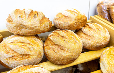 Freshly baked  loaves of bread displayed on wooden shelves in bakery