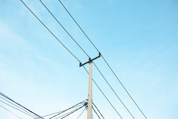 Fototapeta premium Electric power pole and overhead cables under clear blue sky in daylight