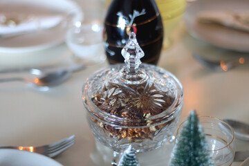 Table set for Christmas meal, with plates, wine, decorations and lit candles. Selective focus.	