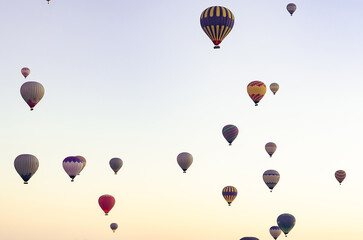 Cappadocia, Turkey. A sky full of colorful hot air balloons drifting peacefully at sunrise above the ancient volcanic landscape. A serene and cinematic morning scene.