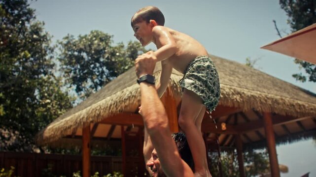 Father and son playing in pool at tropical villa resort