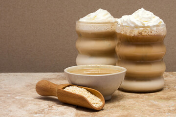 Creamy Tahini Latte Coffee and with tahini cream bowl and sesame seeds on a marble travertine